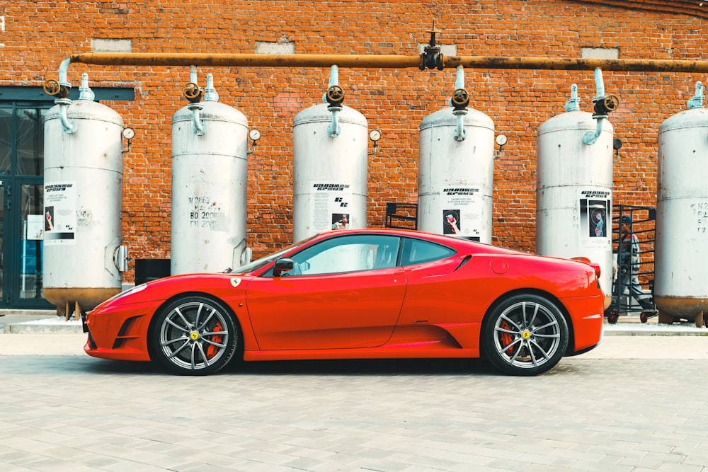 red ferrari 458 italia parked beside white propane tank