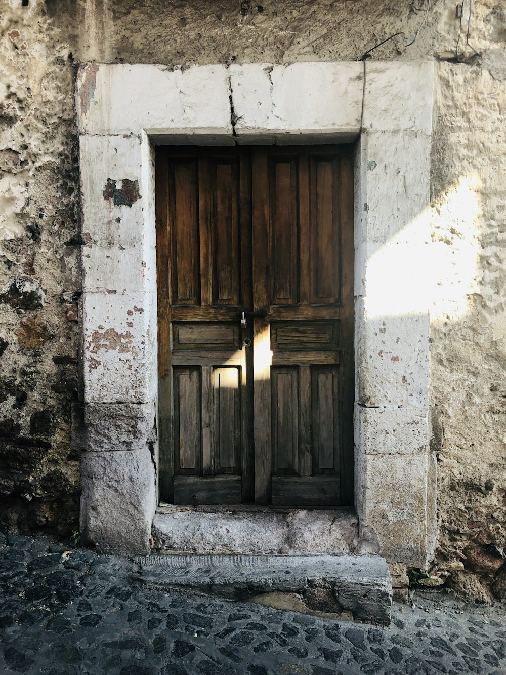 puerta de madera marrón sobre pared de hormigón blanco