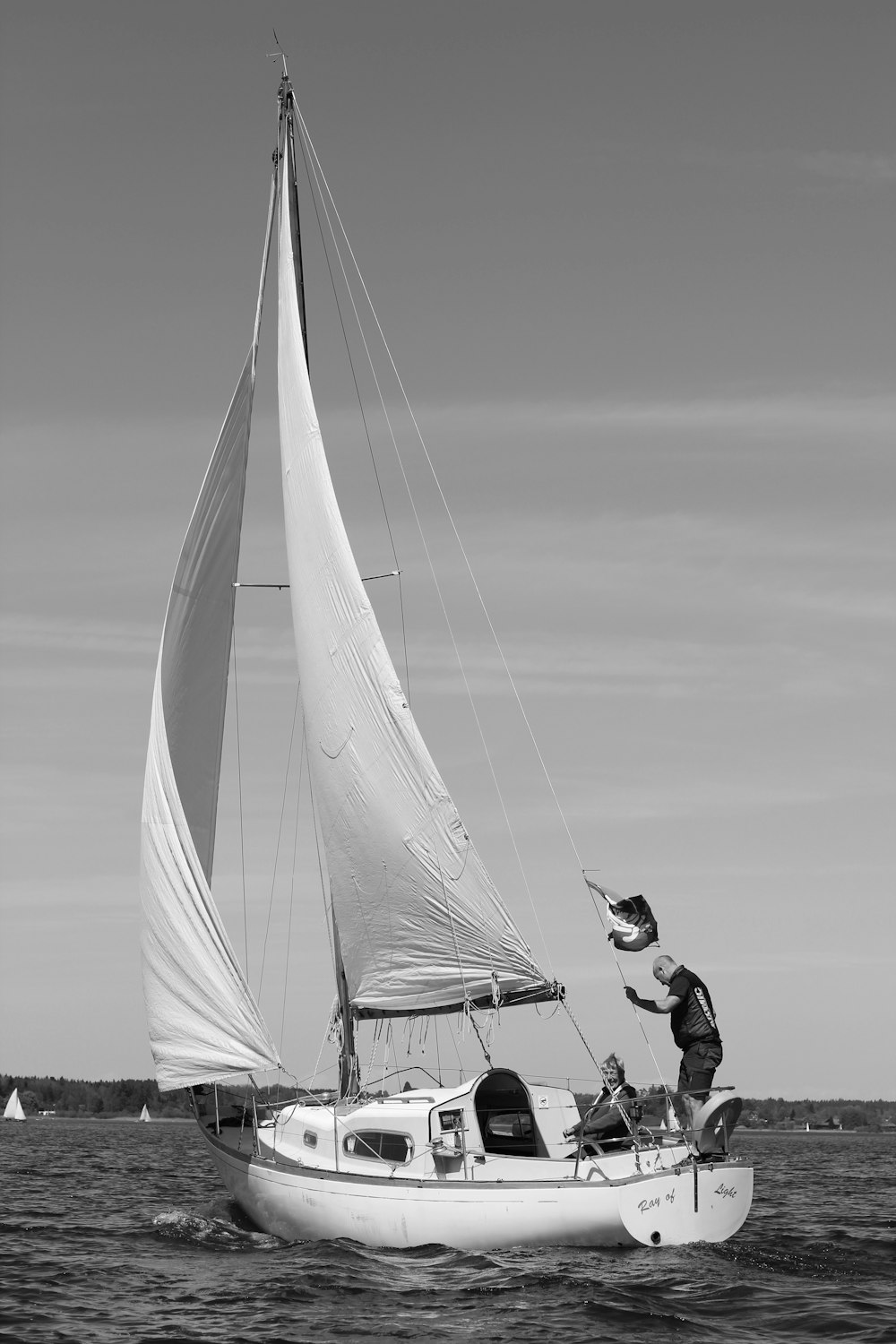 man in black jacket sitting on white sail boat on sea shore