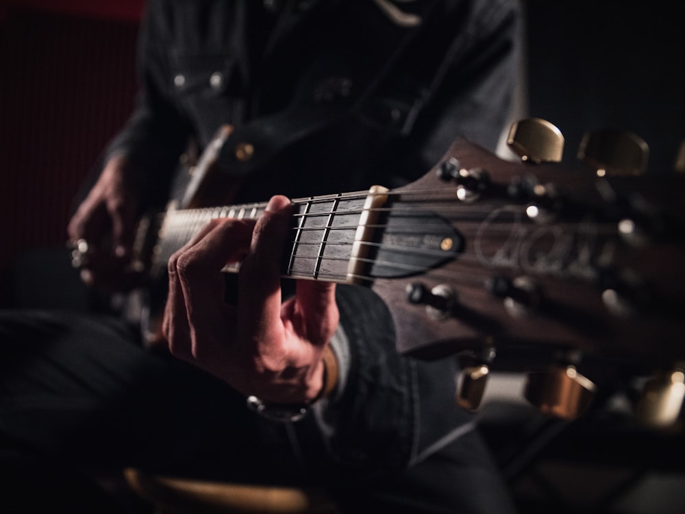 hombre con chaqueta negra tocando la guitarra