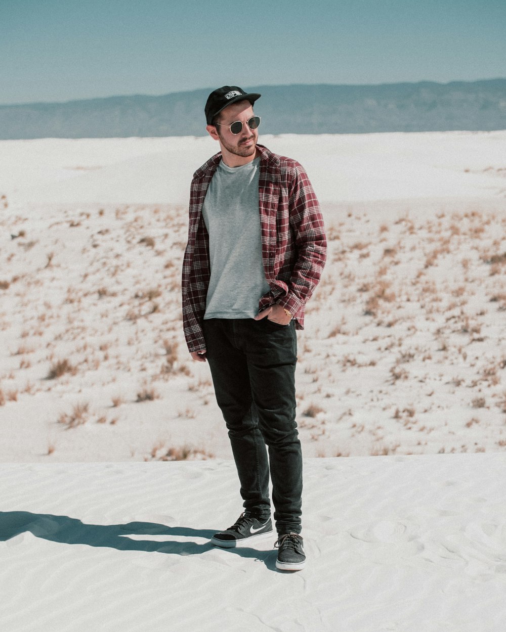 man in red and white plaid dress shirt and black pants standing on white snow during