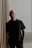 man in black crew neck t-shirt standing near brown curtain