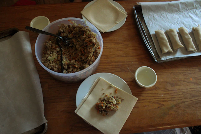 Chef guiding a small group through the art of wrapping Thai spring rolls.