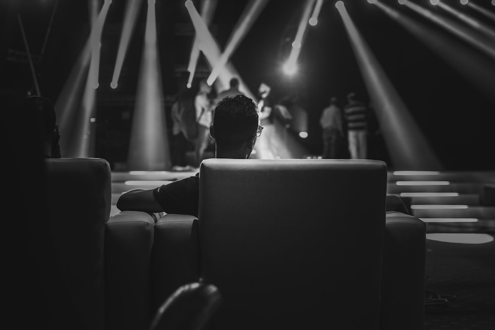 grayscale photo of people sitting on chair