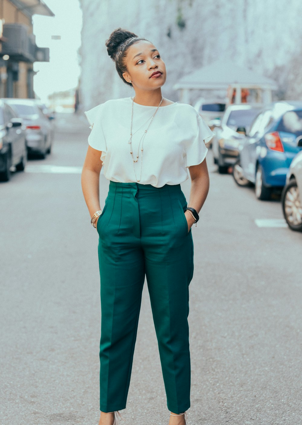 donna in camicia bianca e pantaloni neri in piedi sulla strada durante il giorno