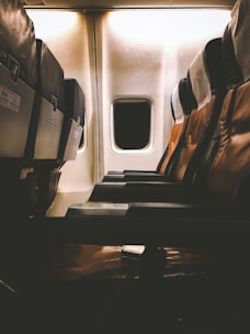 A sleek business class airplane cabin with plush leather seats and ambient lighting.