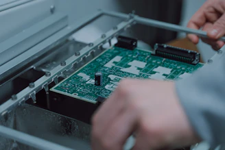 Close-up of a technician assembling a complex PCB prototype in a bright, modern lab.