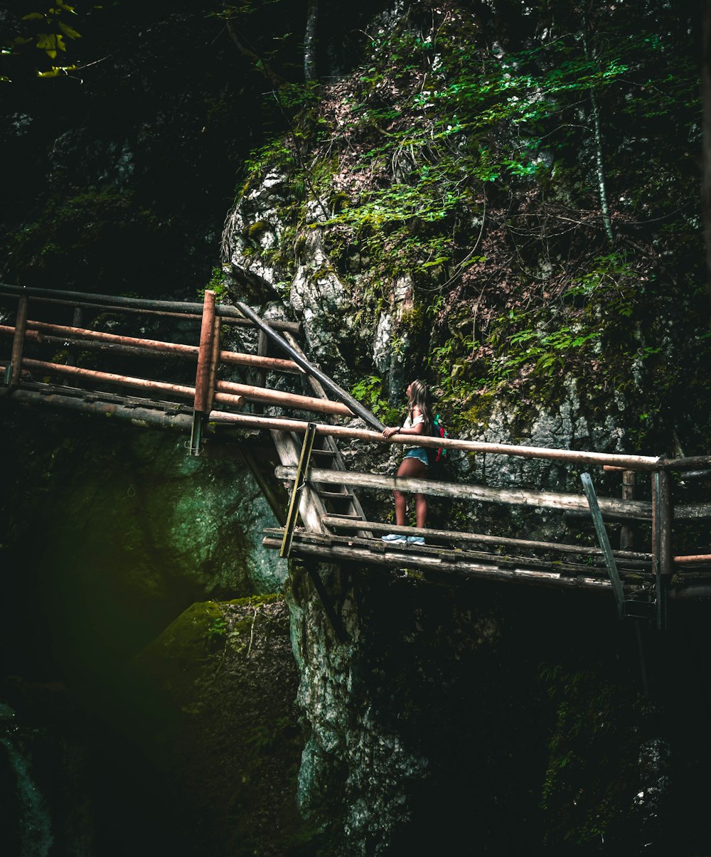 woman in black shirt standing on brown wooden bridge