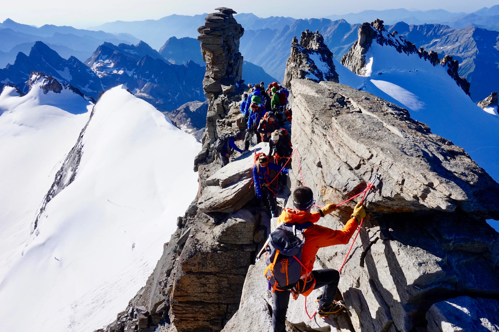 Climbers roped together along a narrow, exposed mountain ridge