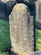 Hands carefully brushing moss and lichen off a marble grave surface.