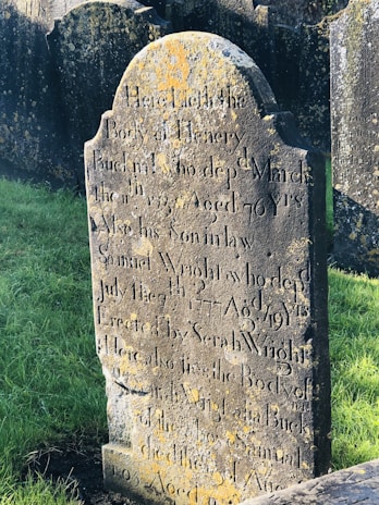 Before and after side-by-side of a moss-covered gravestone transformed to pristine condition.