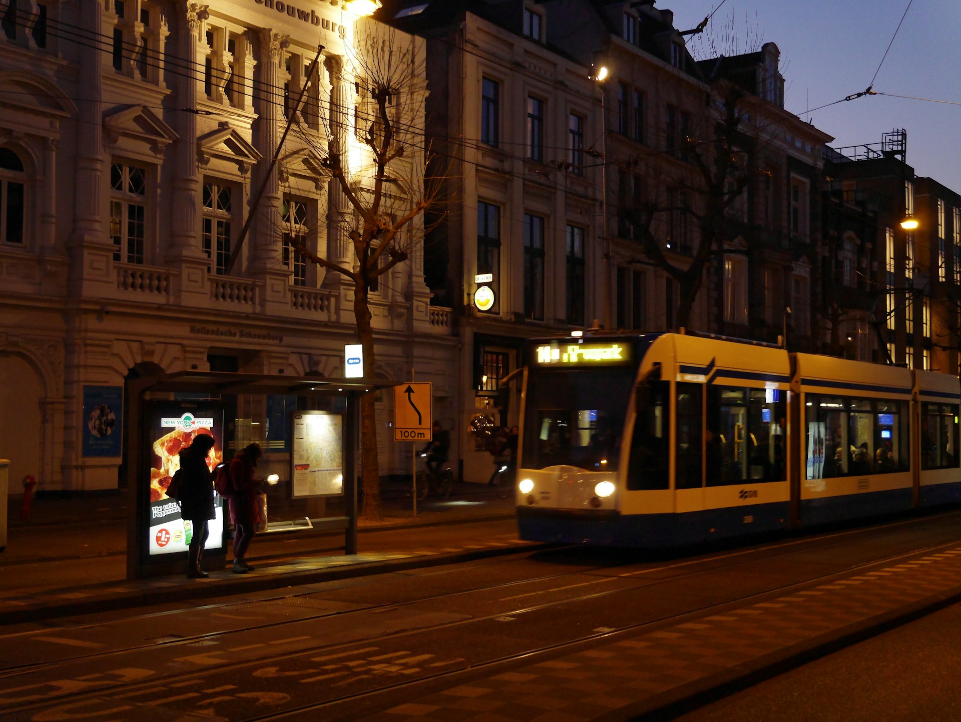 people walking on sidewalk near white and yellow tram during daytime