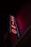 A neon sign is prominently displayed on the side of a building. The sign is vertical and spells out the word 'CASINO' in bold, red neon letters. Surrounding the letters is a blue outline that adds to the vibrancy of the sign against the otherwise dark facade of the building.