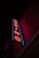 A neon sign is prominently displayed on the side of a building. The sign is vertical and spells out the word 'CASINO' in bold, red neon letters. Surrounding the letters is a blue outline that adds to the vibrancy of the sign against the otherwise dark facade of the building.