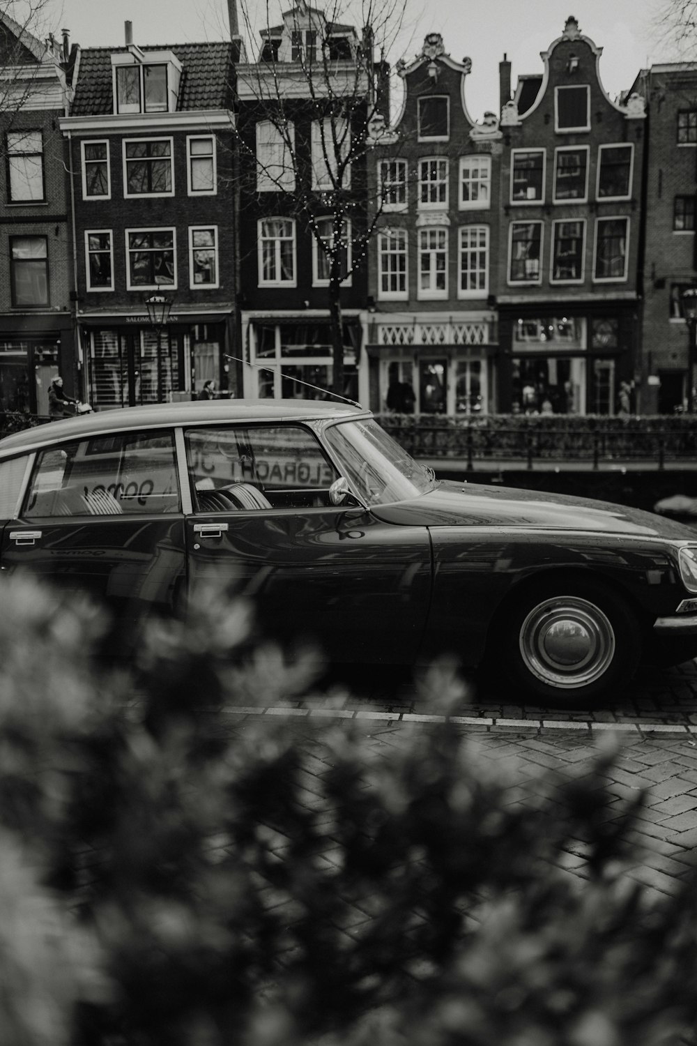 grayscale photo of classic car parked near building
