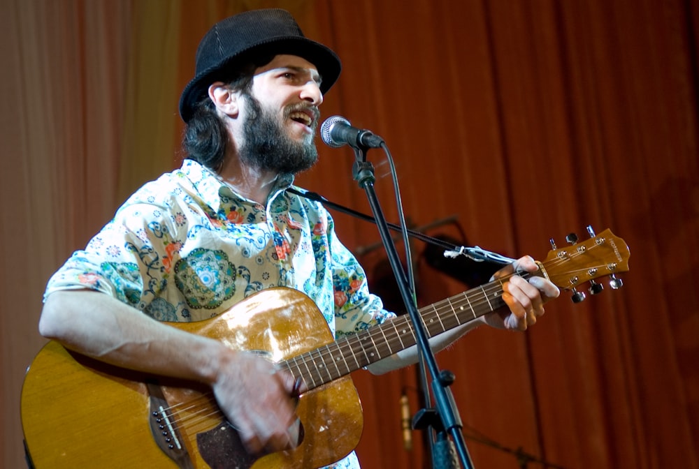 man in white and yellow floral button up shirt playing guitar