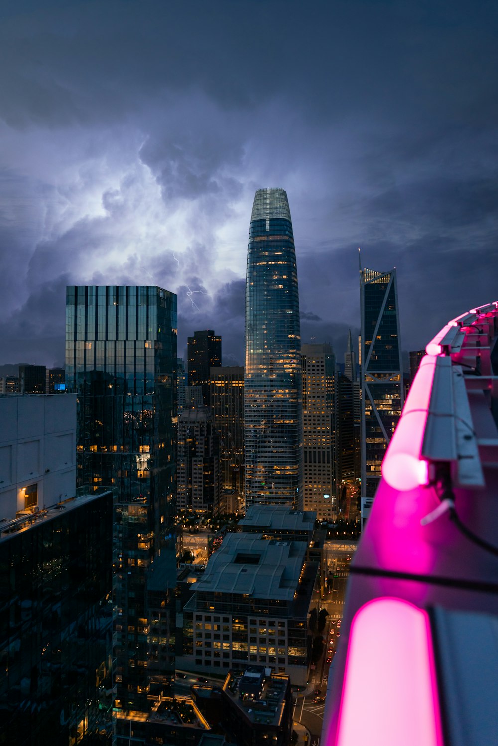 high rise buildings under gray clouds during night time