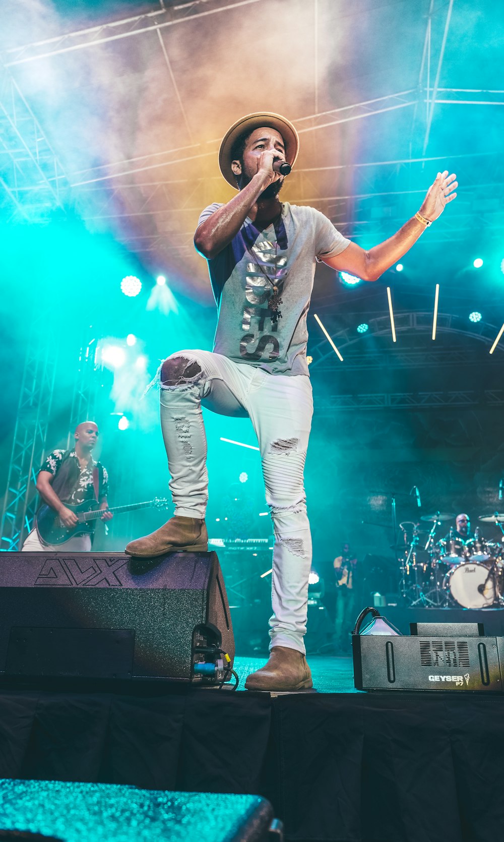 man in black t-shirt and white pants singing on stage