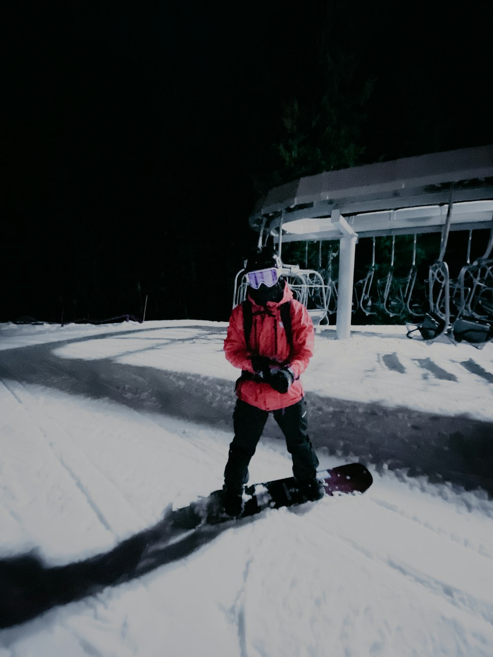 Persona in giacca rossa e pantaloni neri in piedi su terreno coperto di neve durante il giorno