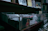 A dimly lit shelf filled with various records or CDs in transparent cases. One case has a label saying 'Special Hawaii' priced at 15€. The shelf is surrounded by other stacks of media, possibly books or albums.