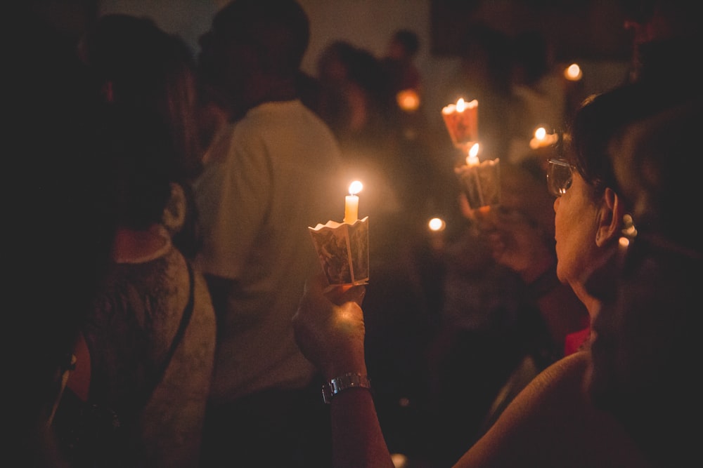 Personas sosteniendo velas encendidas durante la noche