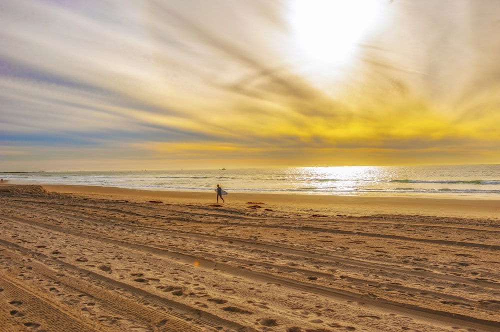 person walking on beach during sunset