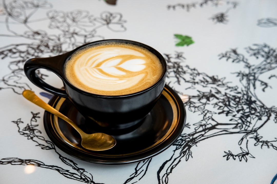 black ceramic cup with saucer on white and black floral textile