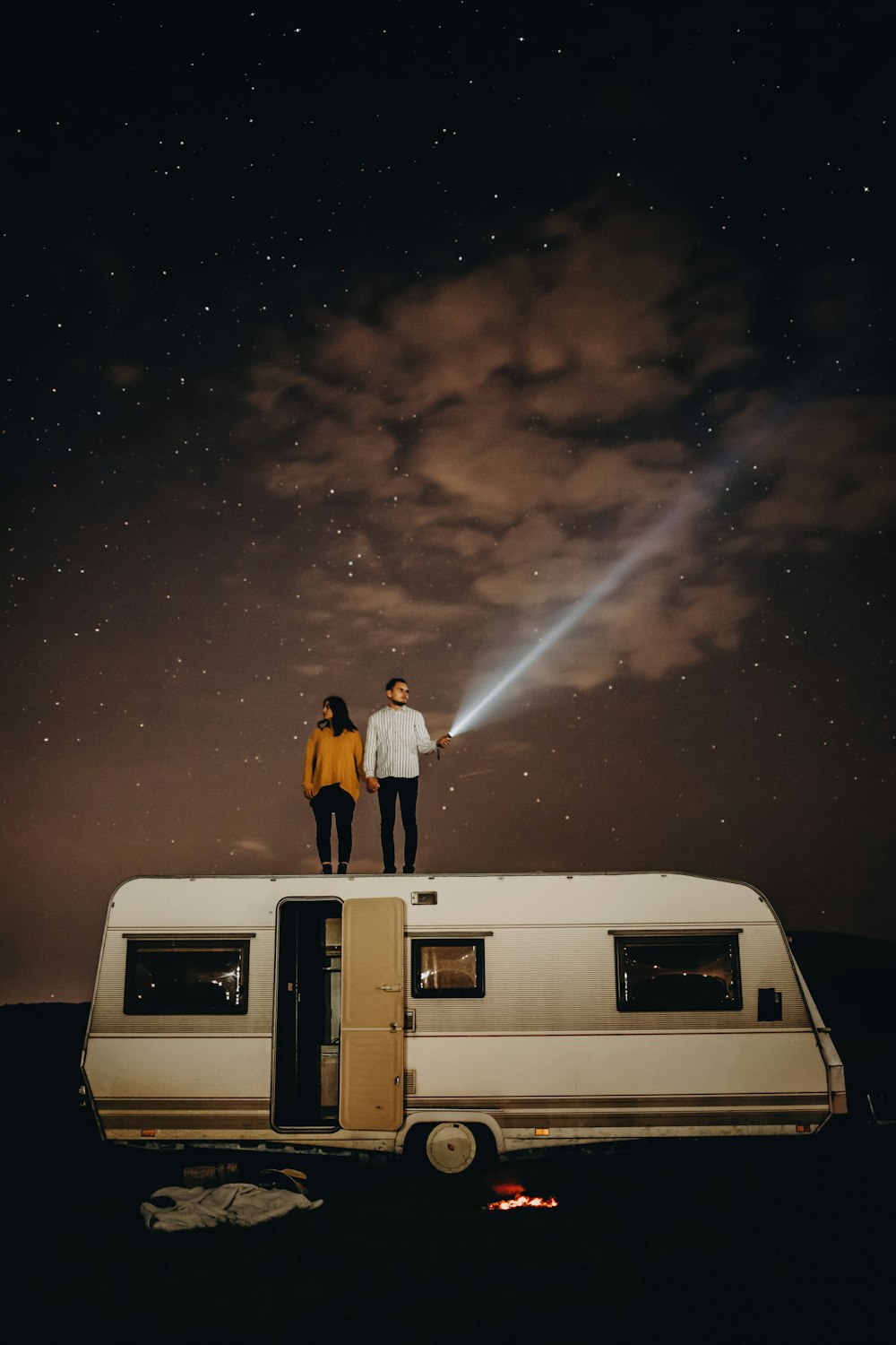 two people standing on top of a trailer under a night sky