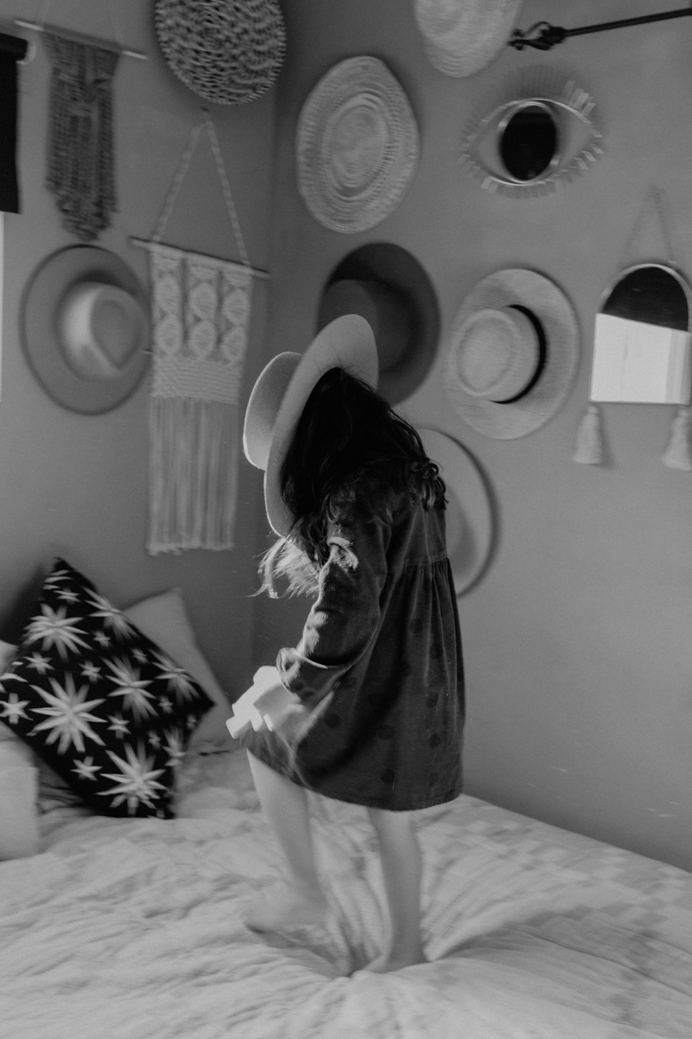 a little girl standing on top of a bed