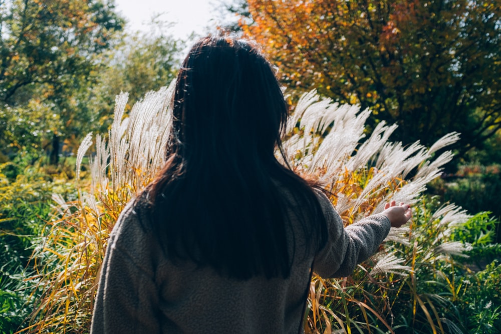 woman in gray sweater standing on green grass field during daytime