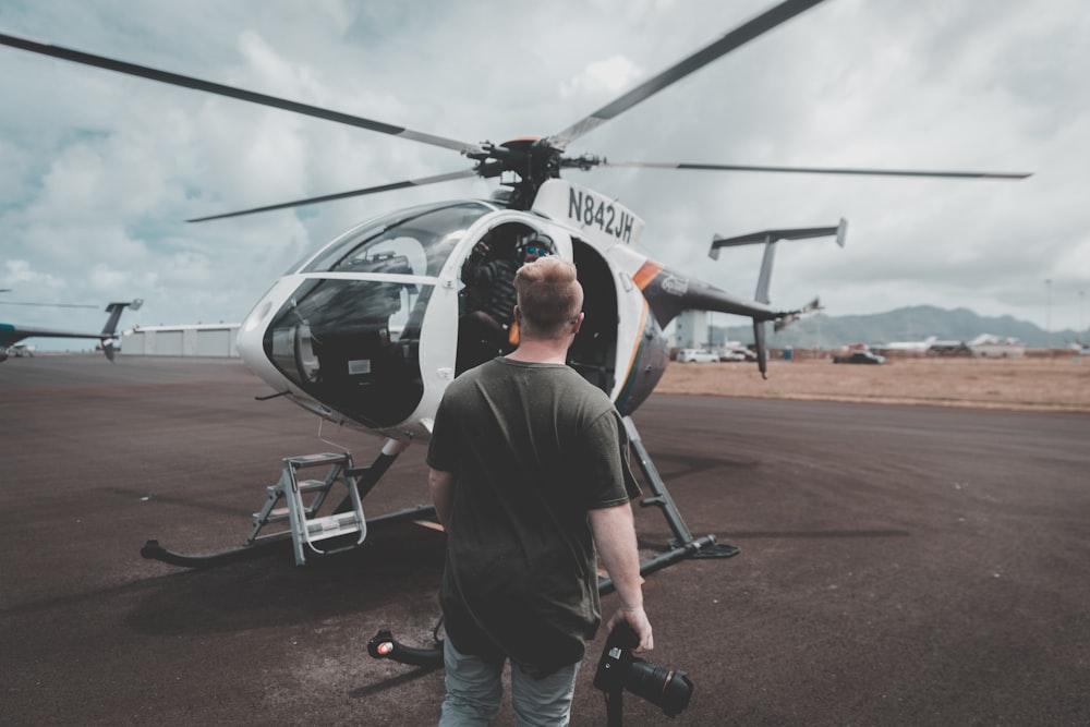 man in black t-shirt and black pants standing near black and white helicopter