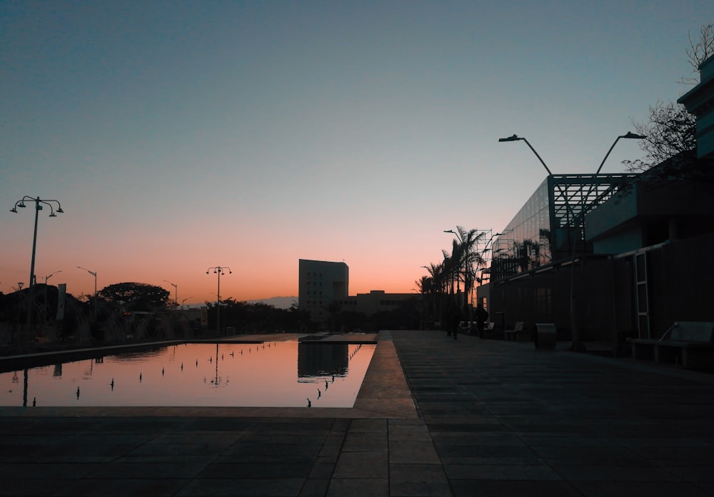 silhouette d’un bâtiment près d’un plan d’eau au coucher du soleil