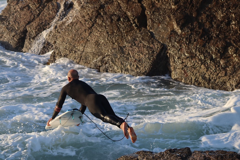 man in black shorts holding white surfboard on water during daytime