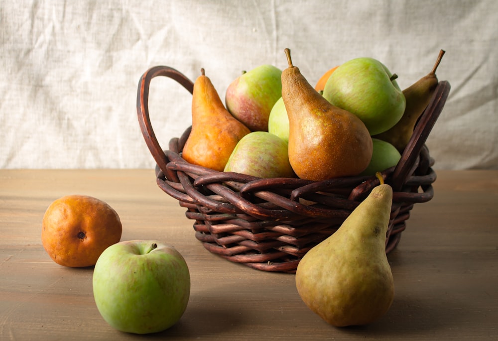 green and yellow apples on brown woven basket