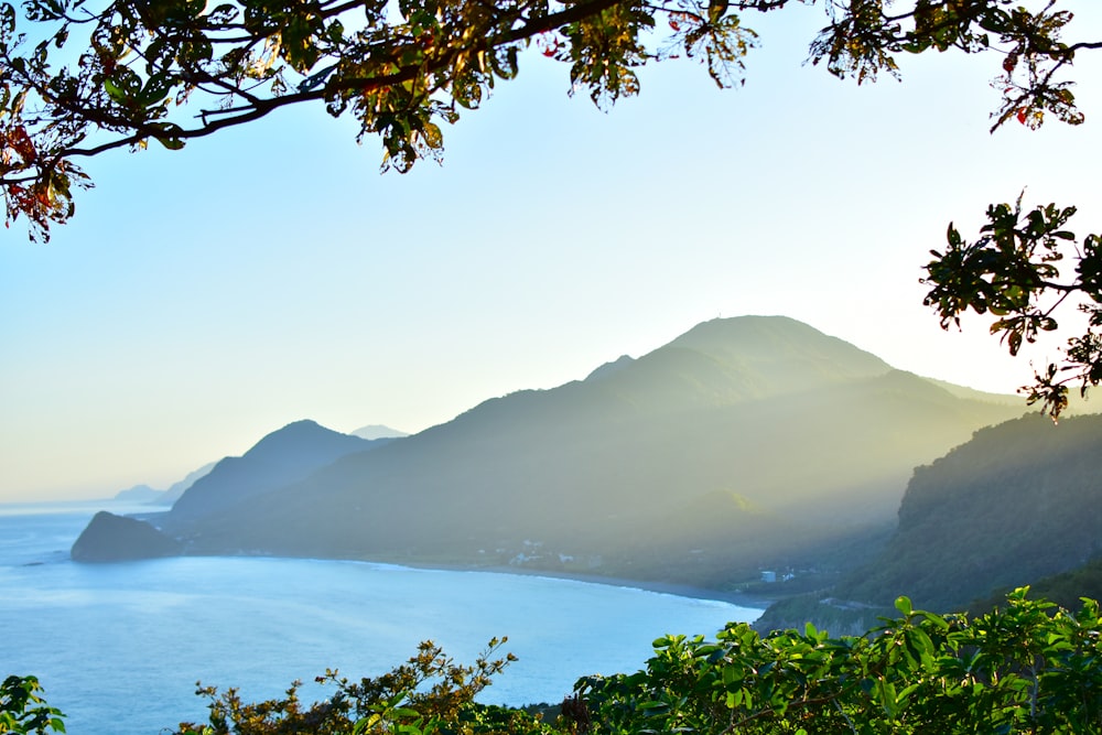 green mountain beside body of water during daytime