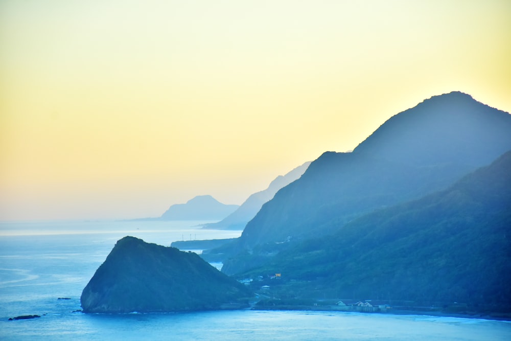 green mountains beside body of water during daytime