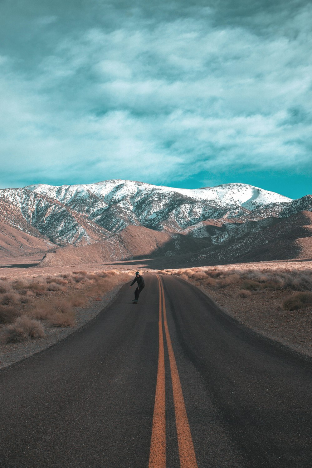 brown dirt road near snow covered mountain during daytime