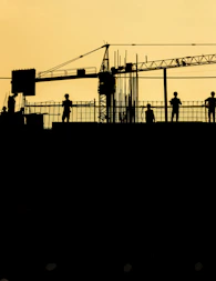 silhouetted construction workers at sunset