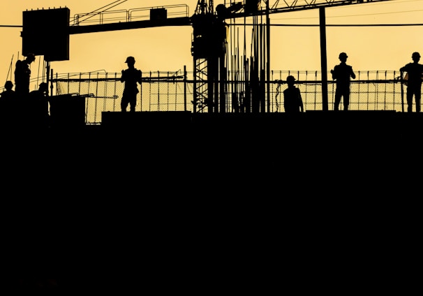 silhouette of people standing on tower crane during night time