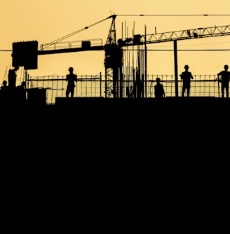 silhouette of people standing on tower crane during night time