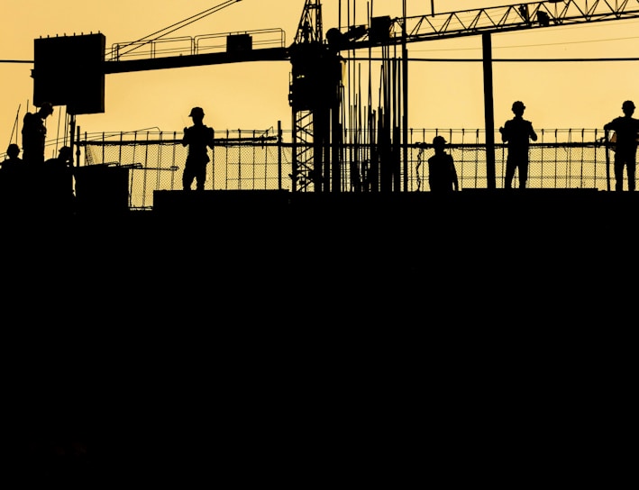 silhouette of people standing on tower crane during night time