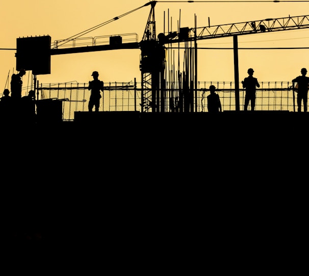 silhouette of people standing on tower crane during night time