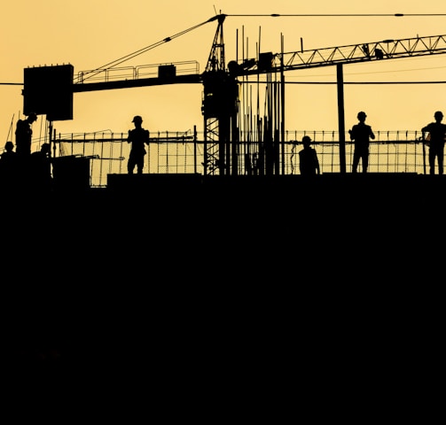 silhouette of people standing on tower crane during night time