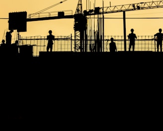 silhouette of people standing on tower crane during night time