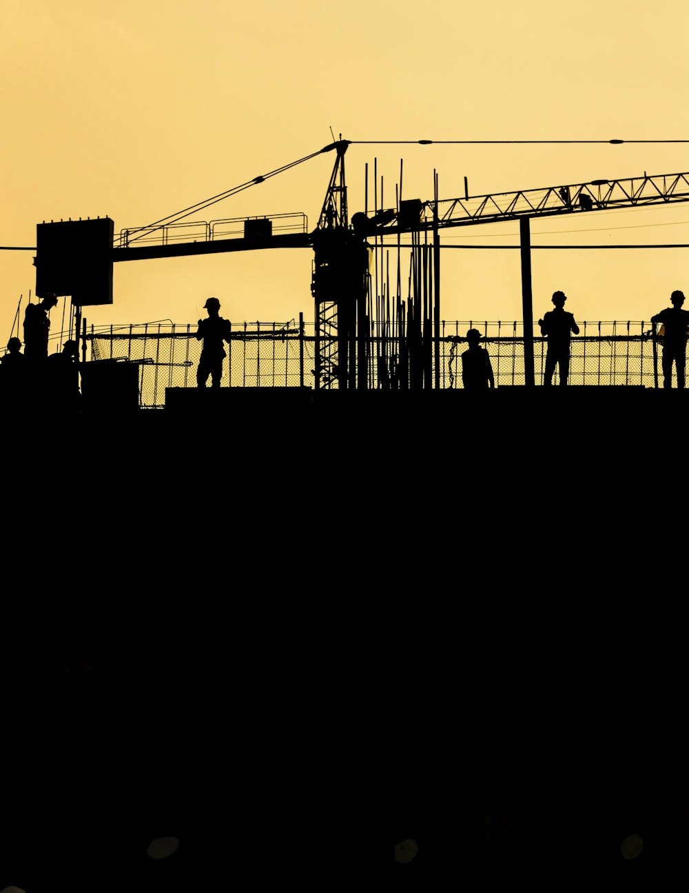 silhouette de personnes debout sur une grue à tour pendant la nuit