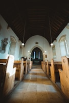 Wide shot of the church interior showcasing ancient wooden pews and stone walls bathed in soft natural light.