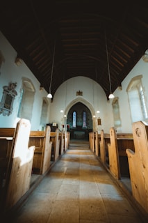 Wide shot of the church interior showcasing ancient wooden pews and stone walls bathed in soft natural light.