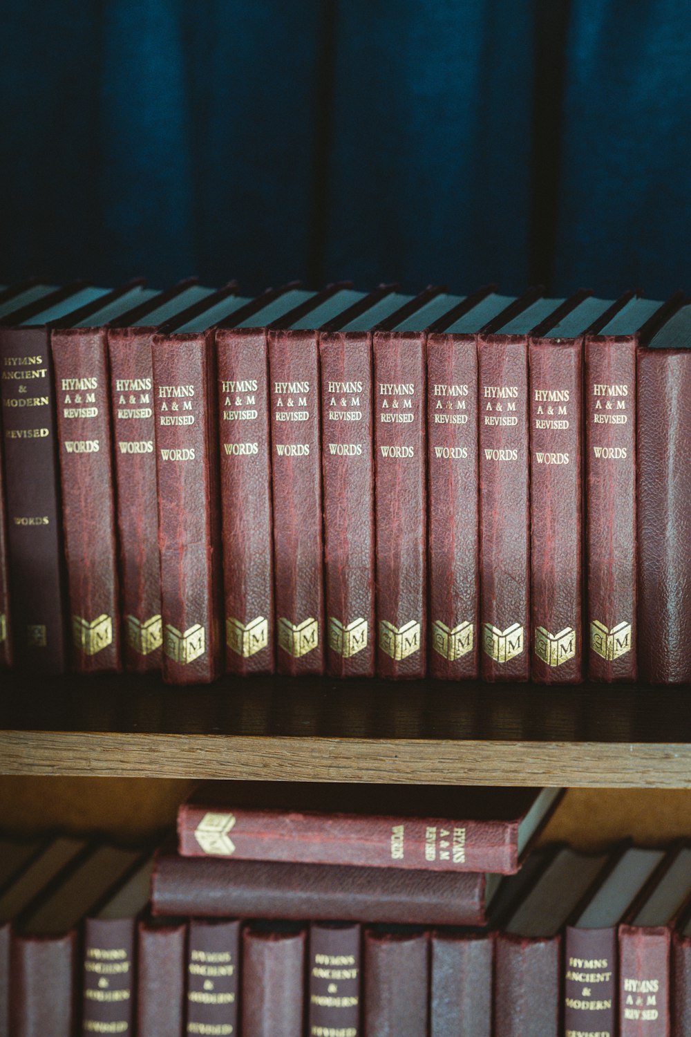 Livres reliés rouge et noir sur étagère en bois marron