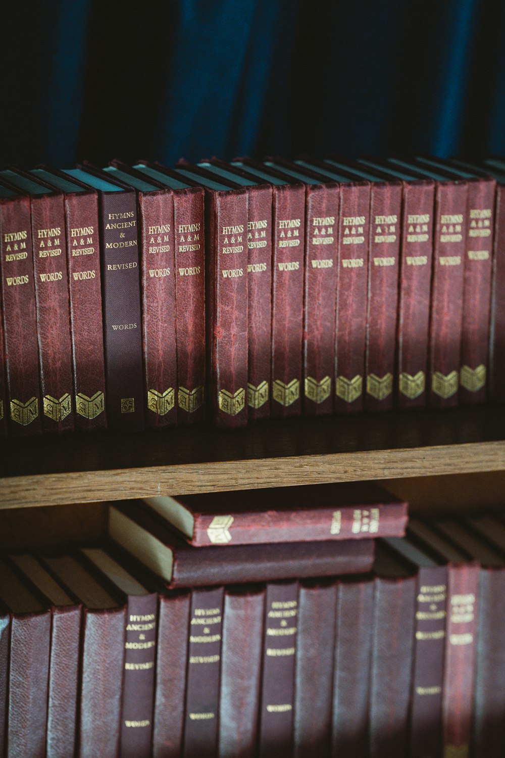 red and black hardbound books on brown wooden shelf