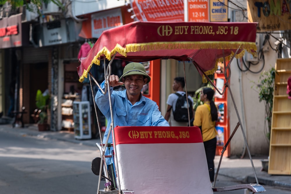 man in blue jacket riding on red and white food cart during daytime